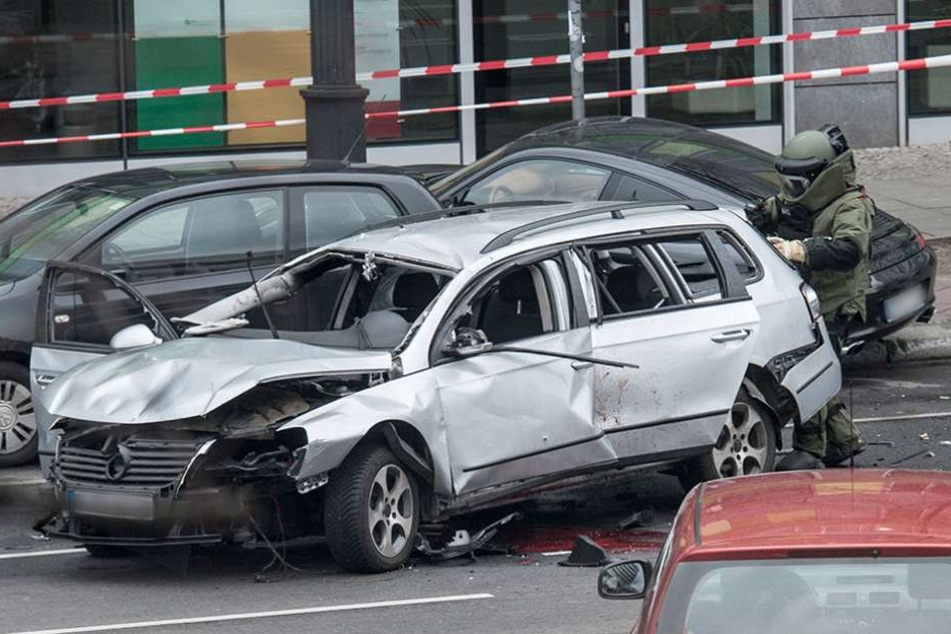 Ein Sprengstoffexperte der Polizei nähert untersucht im Schutzanzug das Auto nach weiteren Sprengsätzen.