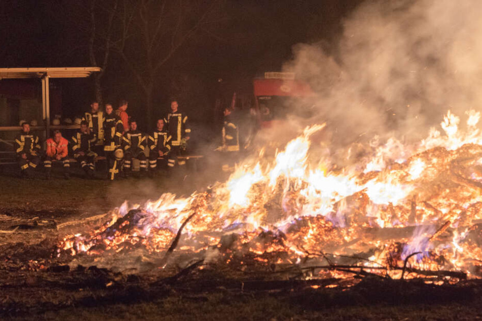 Die Einsatzkräfte schauen beim Abbrennen des Osterfeuers zu.