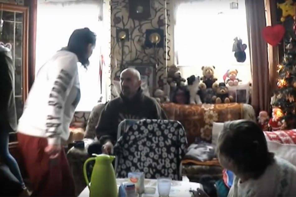 Nachdem Karins Tochter Yvonne (weißer Pullover) die Schnapsflasche von ihrem Bruder Norman (sitzend) versehentlich umgestoßen hat, rastet der aus. Mutter Karin kündigt an: "Der geht heute weg hier, der ist eine Gefahr für die Menschheit".