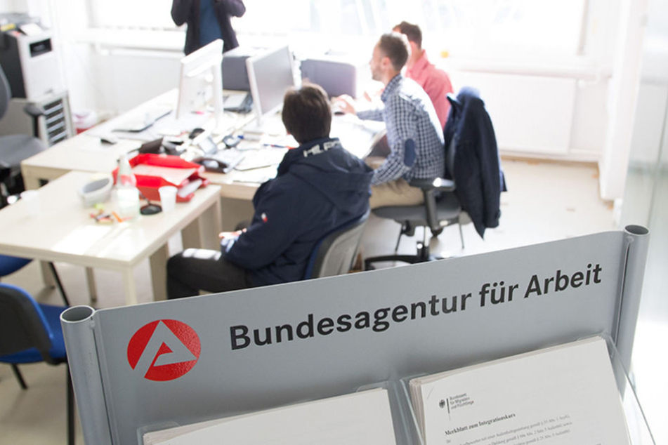 Ein Flüchtling aus Syrien (l) in einem Büro der Agentur für Arbeit neben zwei Sachbearbeitern.