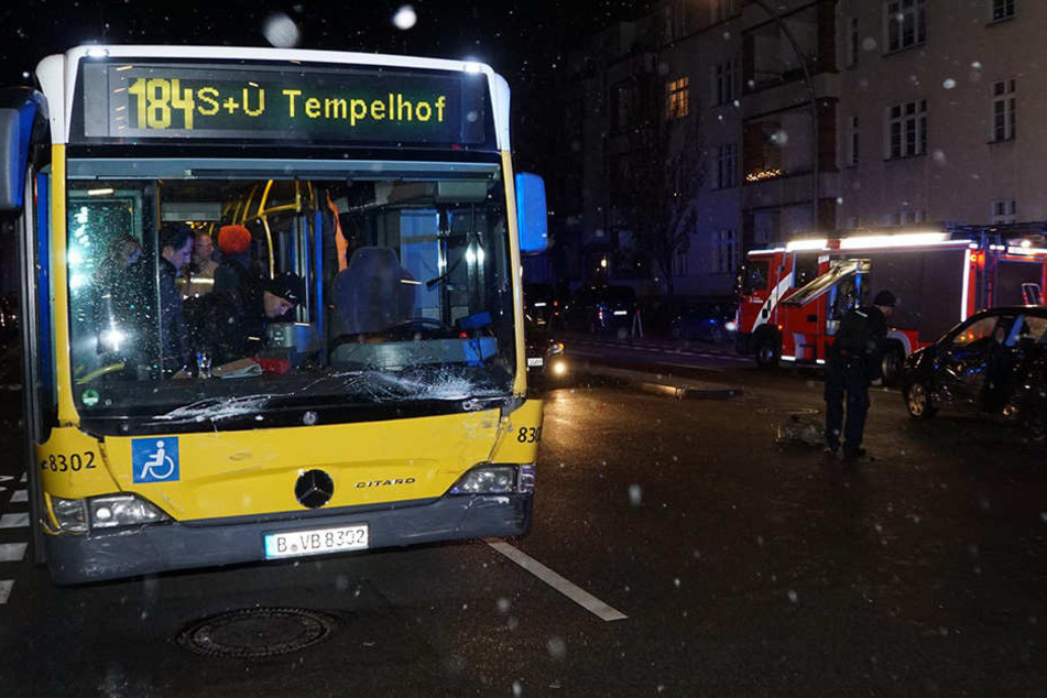 Polizisten und Feuerwehr betrachten den Schaden am Bus und PKW.