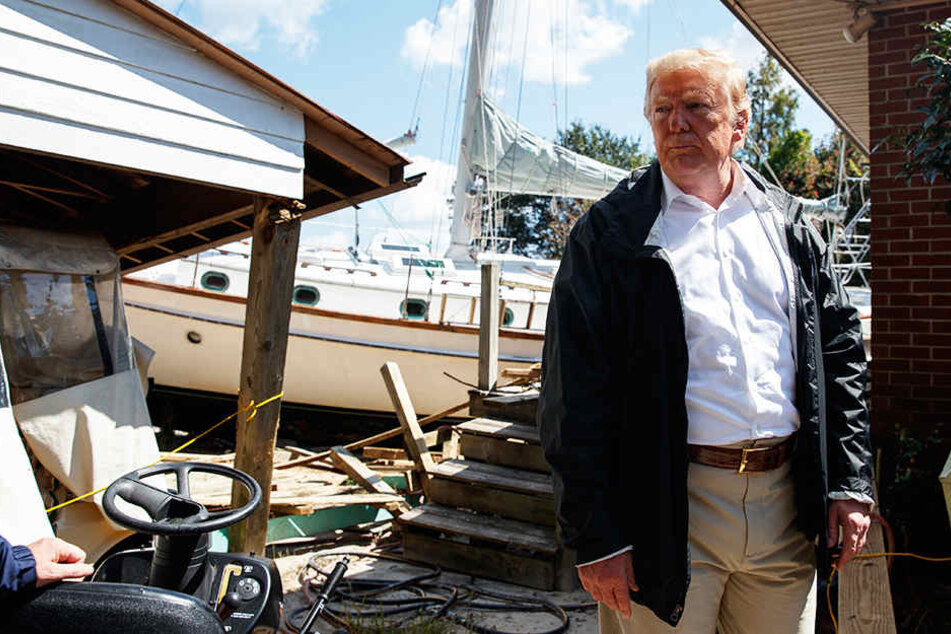 Präsident Donald Trump besucht ein Haus, in dem ein Boot im Hinterhof an Land gespült wurde.