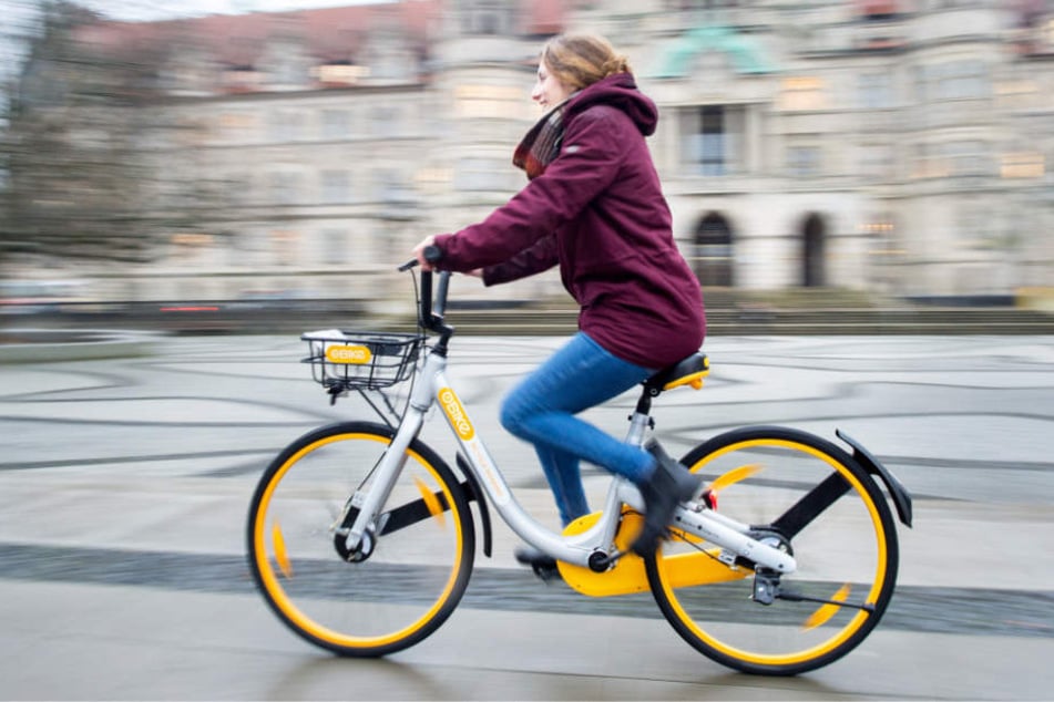 Eine Frau vor dem Neuen Rathaus in Hannover mit einem Leihfahrrad der Firma Obike