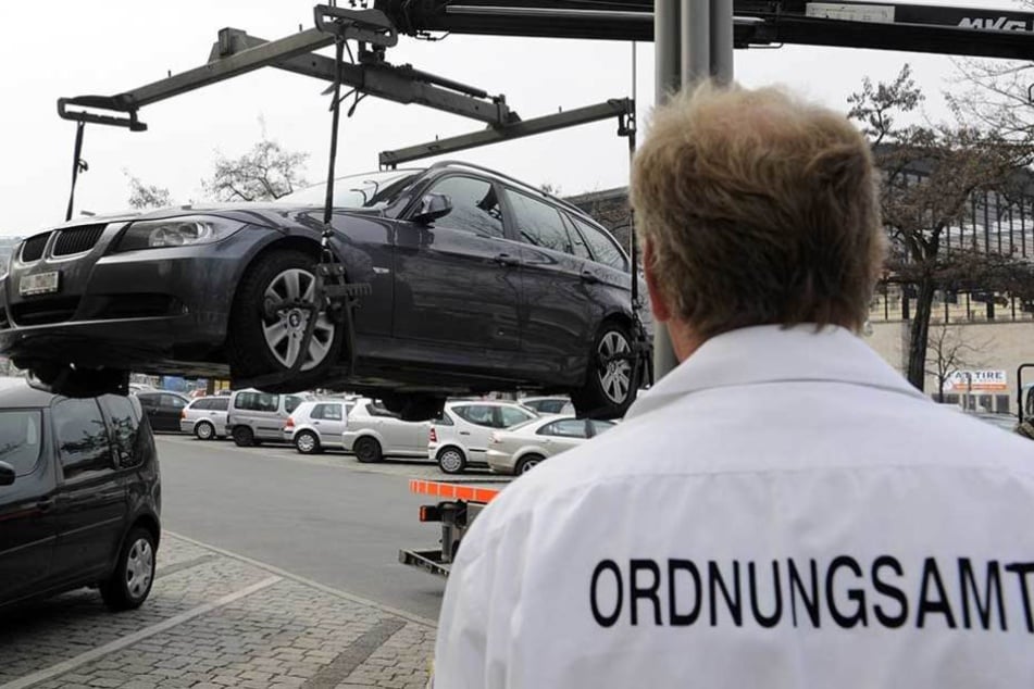 Ein Mitarbeiter des Ordnungsamtes lasst einen BMW abschleppen (Archivfoto).