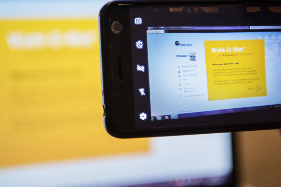Ein Nutzer macht mit dem Smartphone ein Foto vom hessischen "Wahl-O-Mat" auf einem Laptop.