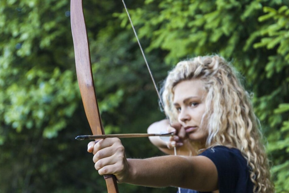 Vorbild "Tribute von Panem"? Eine Frau zielt mit Pfeil und Bogen.