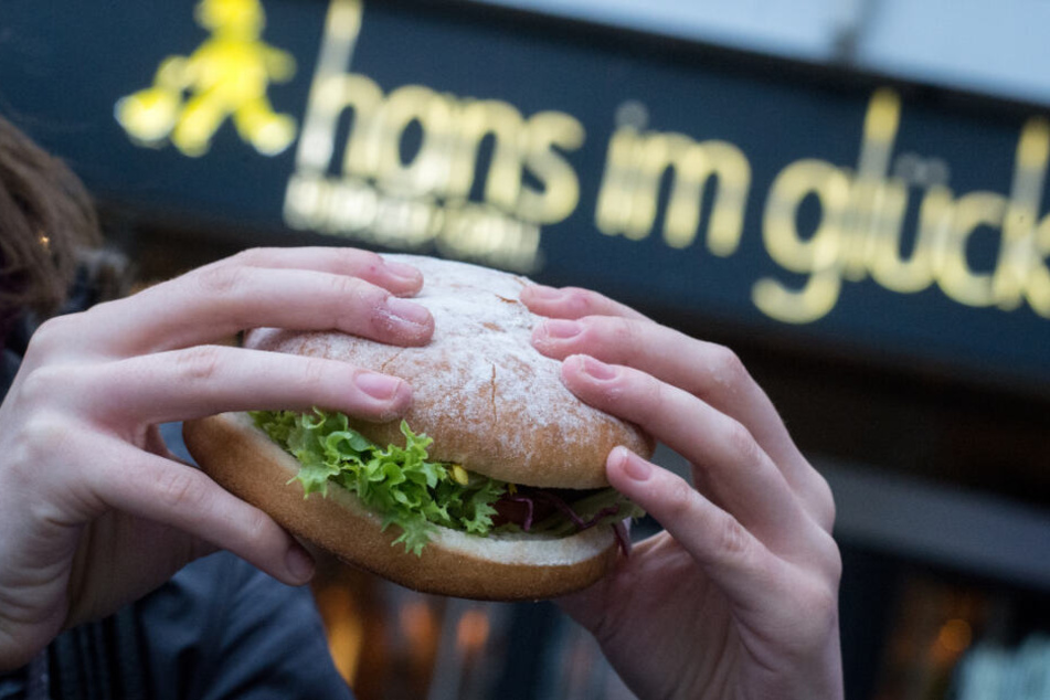 Eine Frau hält einen "Hans im Glück"-Burger in den Händen. (Symbolbild)
