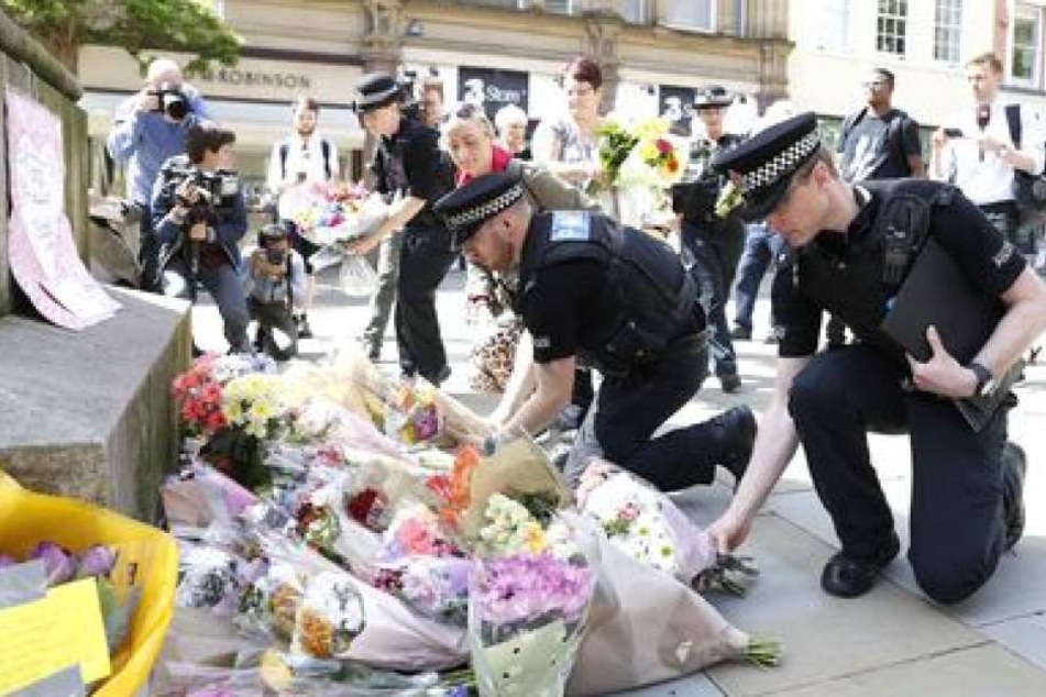 Polizisten legen auf der St Ann's Square in Manchester Blumen ab.