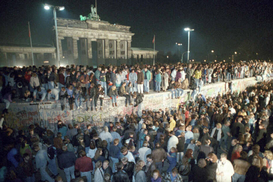 Menschen auf der Berliner Mauer vor dem Brandenburger Tor in der Nacht vom 9. auf den 10.11.1989.