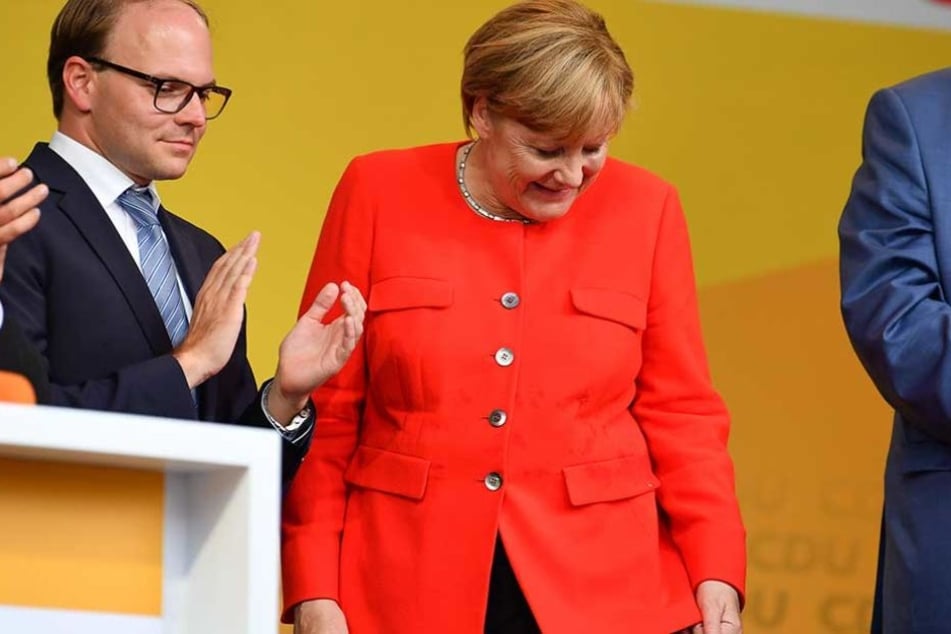 Bundeskanzlerin Angela Merkel schaut auf dem Fleck auf ihrem Sakko, an dem eine Tomate eingeschlagen ist.