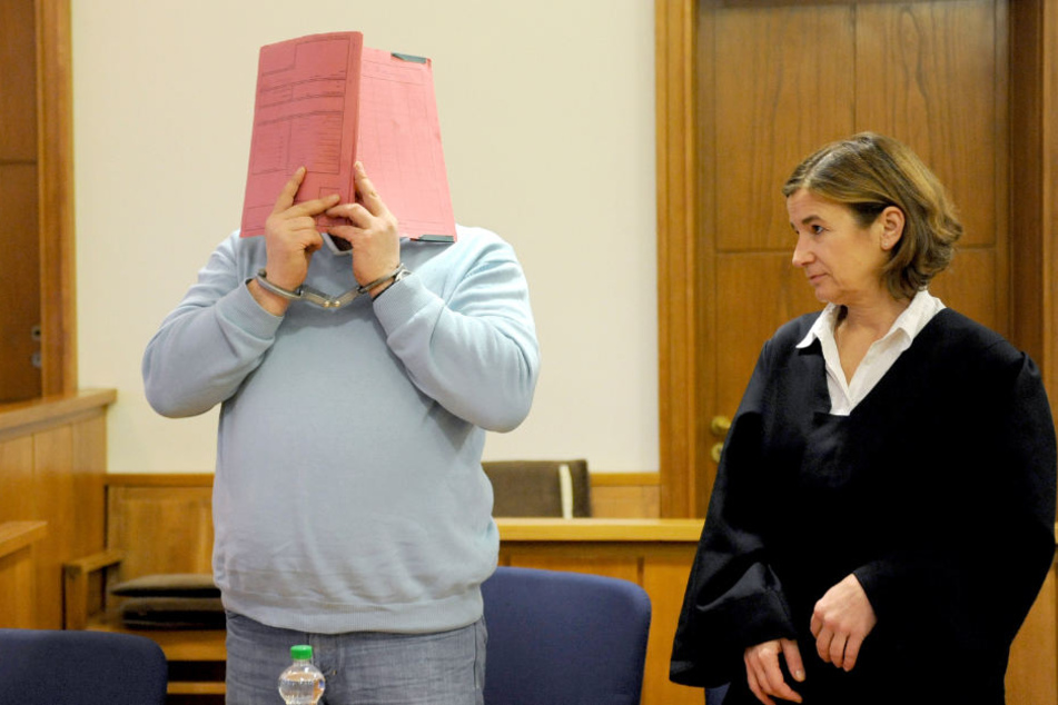 Niels Högel verdeckt sein Gesicht im Landgericht Oldenburg. Neben ihm steht seine Anwältin Ulrike Baumann.
