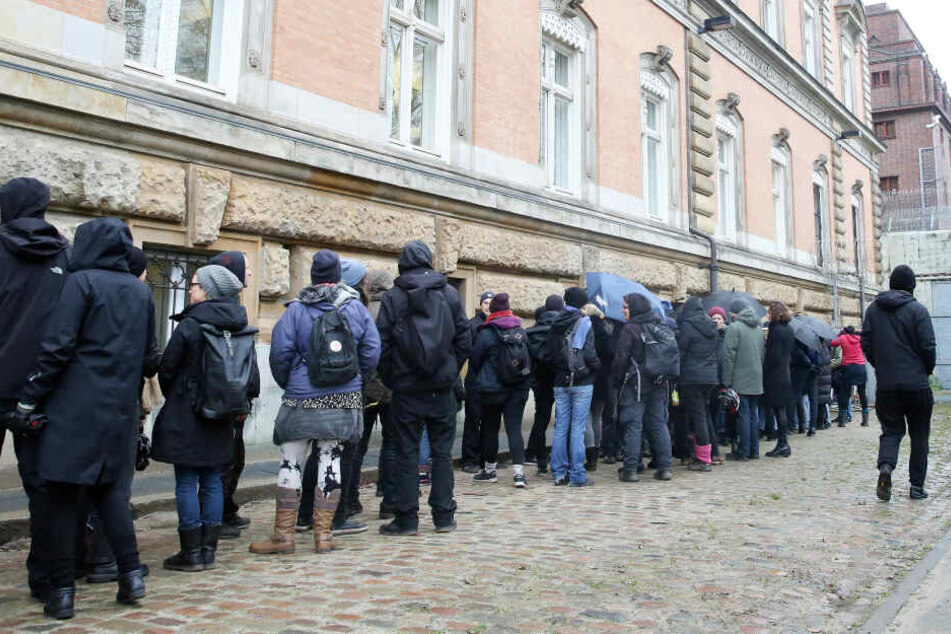 Prozessbesucher warten auf den Zugang zu einem Sitzungsaal, der für Besucher nach einer Kontrolle nur von Außen zu betreten ist.