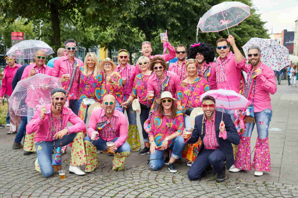 Besucher des Schlagermoves posieren in bunten Kostümen und Perücken auf der Reeperbahn.