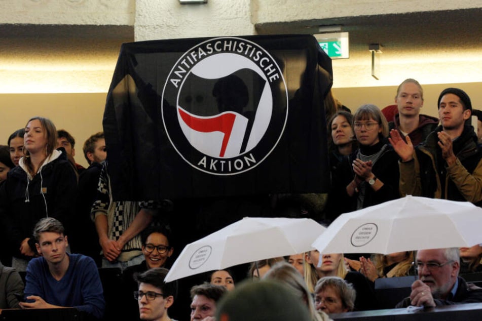 Demonstranten halten im Hörsaal der Uni Hamburg eine Fahne der Antifa hoch.