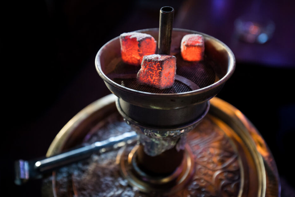 Glühende Kohle liegt auf einem Metallsieb einer Wasserpfeife in einer Shisha-Bar. Betreiber solcher Rauchertreffs sollen in Hamburg per Gesetz zum Schutz ihrer Gäste verpflichtet werden.