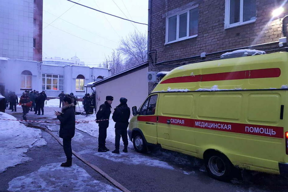 Ein Krankenwagen und Polizisten stehen vor dem Hotel im russischen Perm.
