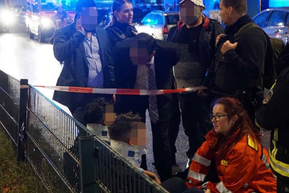 Vermutlich Familienangehörige reden auf die verletzten Unfallfahrer und Rettungskräfte ein.