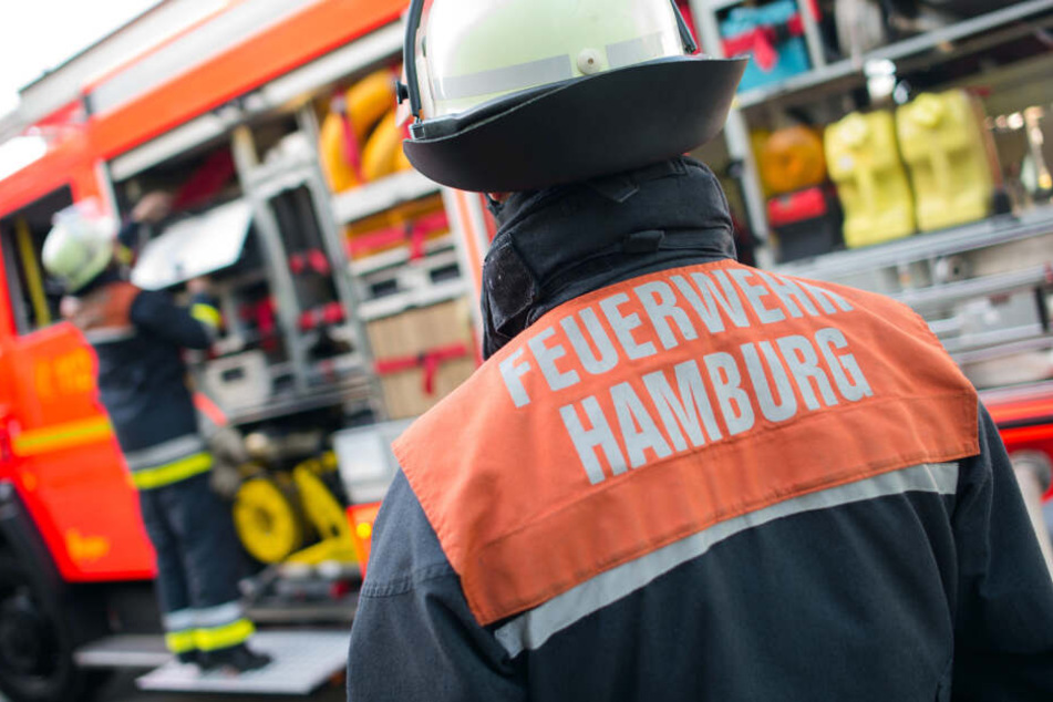 Ein Feuerwehrmann der Hamburger Feuerwehr steht während einer Übung an einem Löschfahrzeug. Am europaweiten Tag des Notrufs will sich die Hamburger Berufsfeuerwehr am Montag besonders transparent auf Twitter zeigen.