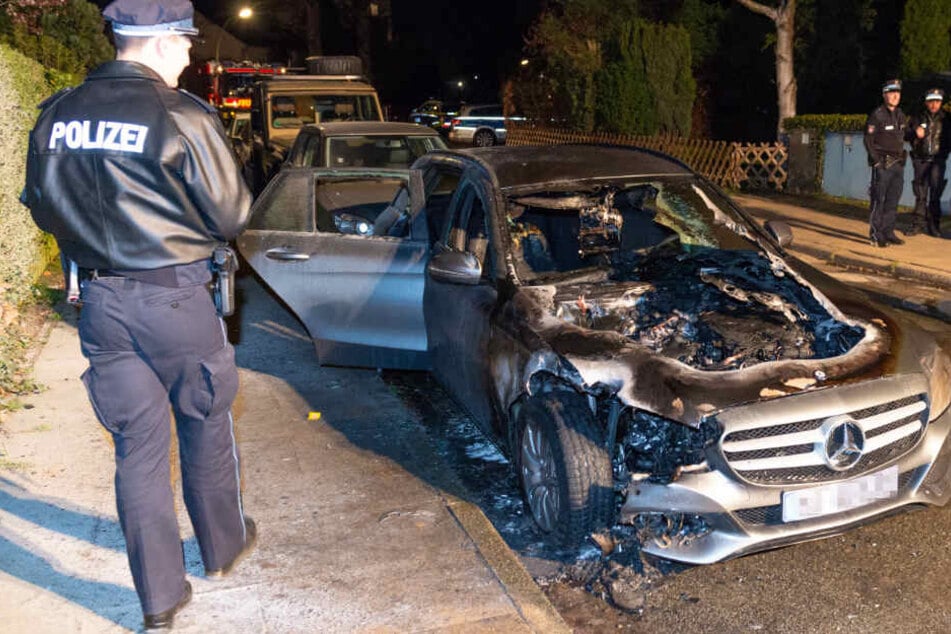 Ein Polizeibeamter begutachtet das durch die Flammen zerstörte Fahrzeug.