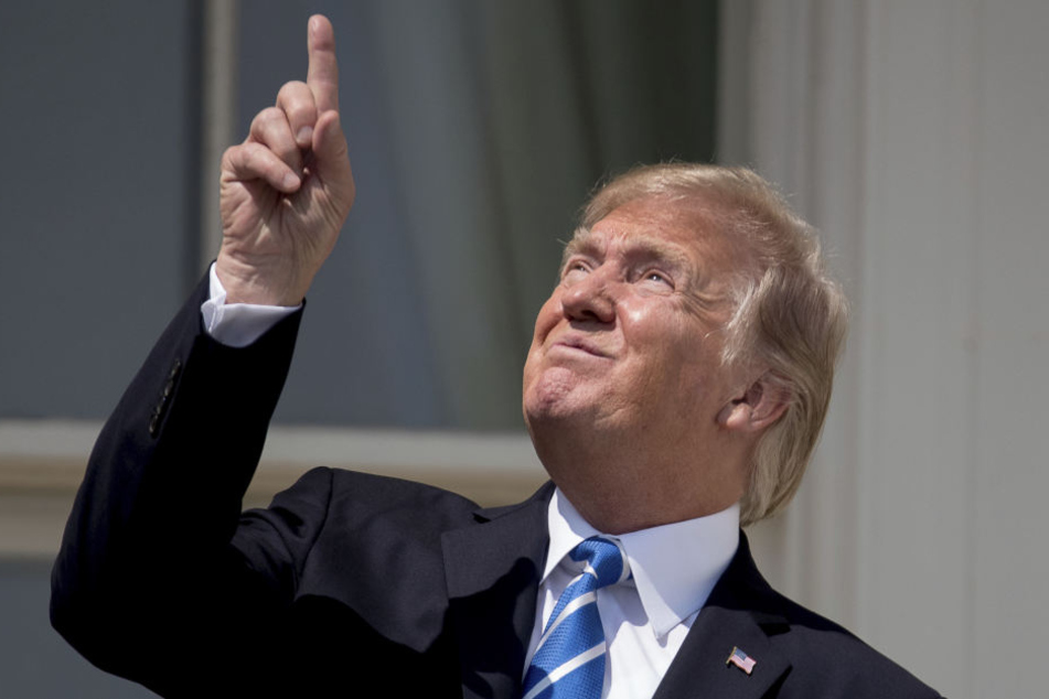 Trump schaut mit zusammengekniffenen Augen in Richtung Sonne.