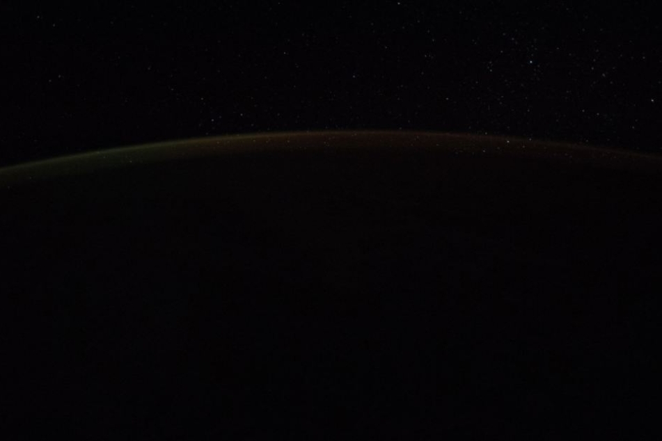 Wer genau hinsieht, sieht einen hellen Streifen am Horizont der Erde.