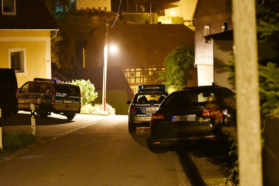 Mehrere Einsatzfahrzeuge der Polizei stehen vor dem Wohnhaus, in dem sich der Täter verschanzte.