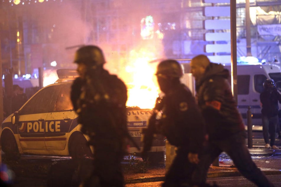 Die Polizei nimmt Position in der Nähe eines brennenden Polizeiwagens ein, bei einem Protest der sich gegen den Sanierungsstau in der Stadt richtet.