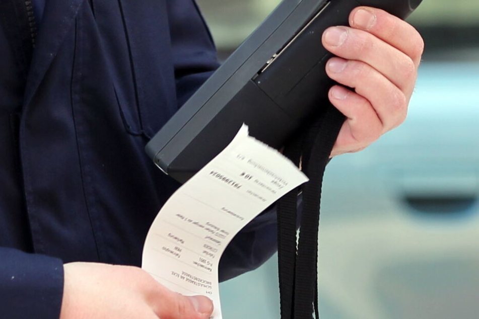 Ein Verkehrspolizist druckt einen Strafzettel aus. (Symbolbild)