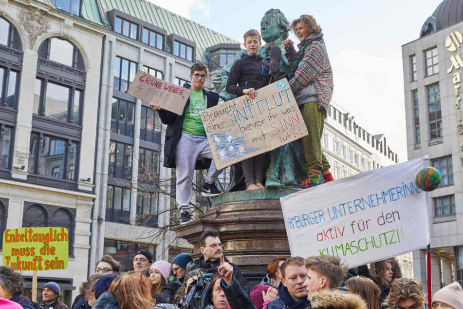 Klimaaktivisten halten auf dem Lessing-Denkmal am Gänsemarkt Transparente unter anderem mit der Aufschrift: "Grüne Wende sonst Ende" und "Enkeltauglich muss die Zukunft sein" hoch.