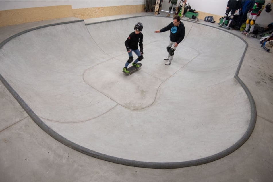 Der Lehrer leitet einen Schüler in der Skateboard-Anlage des Gymnasiums an.