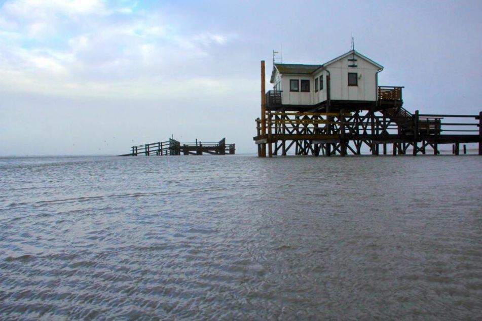 Ein Pfahlbau steht am während einer kleinen Sturmflut am Strand von Sankt Peter-Ording in Schleswig-Holstein im Wasser.