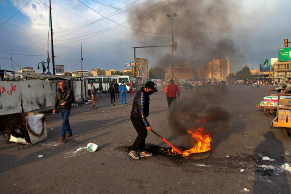 Ein Demonstrant legt während eines Protests gegen den iranischen Raketenangriffe auf US-Stützpunkte im Irak in der Nähe des Tahrir-Platzes in Bagdad ein Feuer.
