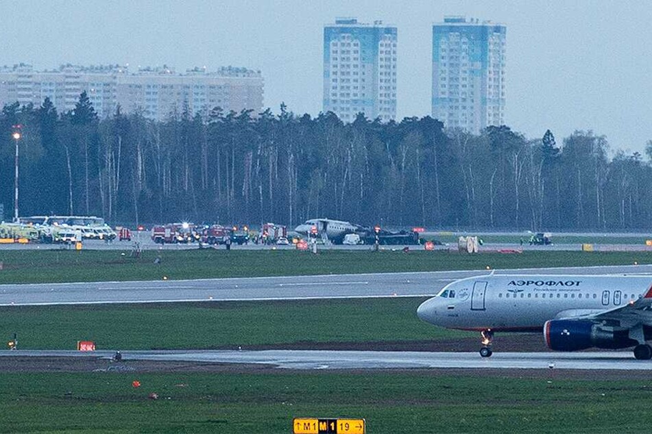 Eine Aeroflot-Maschine des Typs Suchoi Superjet-100 steht nach Löscharbeiten auf dem Rollfeld des Flughafens Scheremetjewo und ist von Einsatzkräften umgeben.