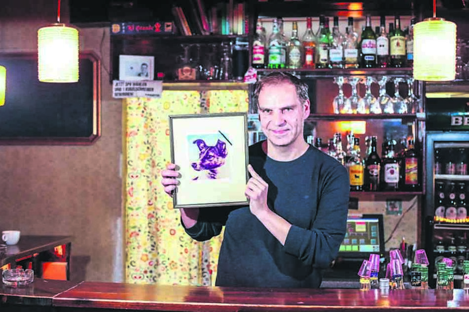 „Laika“-Chef Kristian Münder (48) zeigt das Kneipenfoto Laikas mit
Trauerflor: Am Freitag gibt‘s einen speziellen Laika-Cocktail.