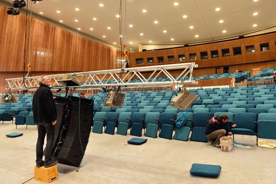 Arbeiter bauen im Auditorium die Sitze wieder ein.