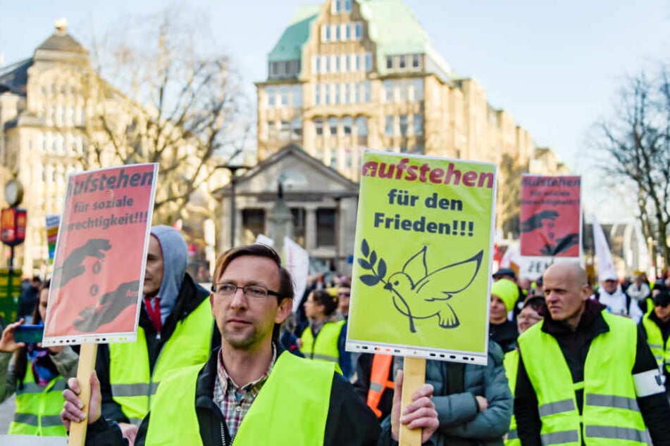 Mit Plakaten für soziale Gerechtigkeit und Frieden ziehen Menschen in gelben Westen während einer Demonstration durch Hamburg.