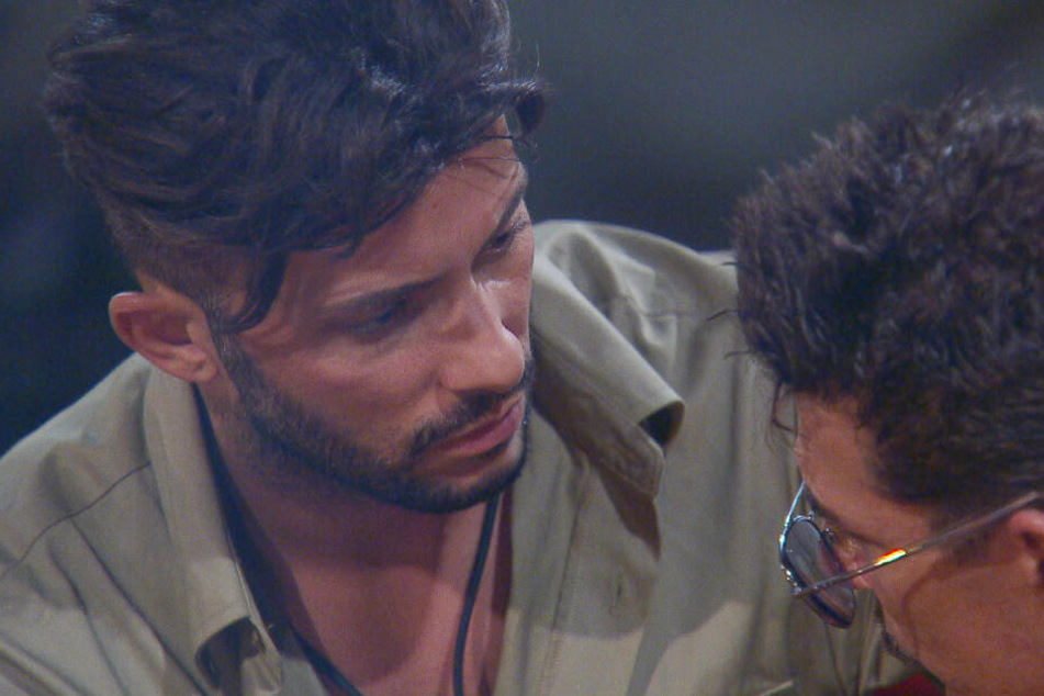 Am Lagerfeuer bringt Domenico (l.) Nataschas Ex, Umut Kekilli, ins Spiel. Er soll was mit Evelyn gehabt haben. Chris ist erstaunt.