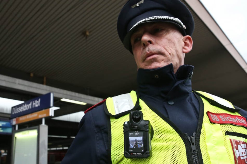 An der Weste eines Sicherheitsmitarbeiters der Deutschen Bahn hängt eine Bodycam.