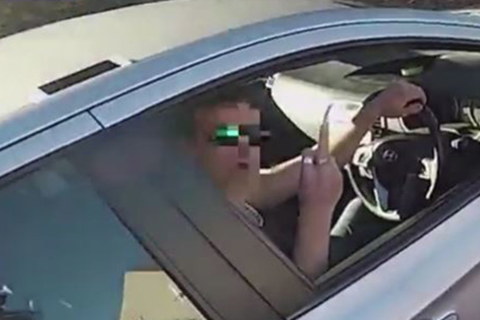 Statt dem Biker dankbar zu sein, zeigt der Autofahrer im noch den Mittelfinger.