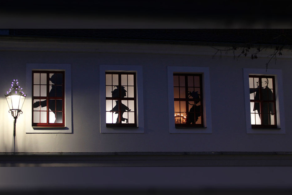 Plauener Weihnachts-Männel: Vater und Sohn schmücken als Schattenbilder das Erich-Ohser-Haus.