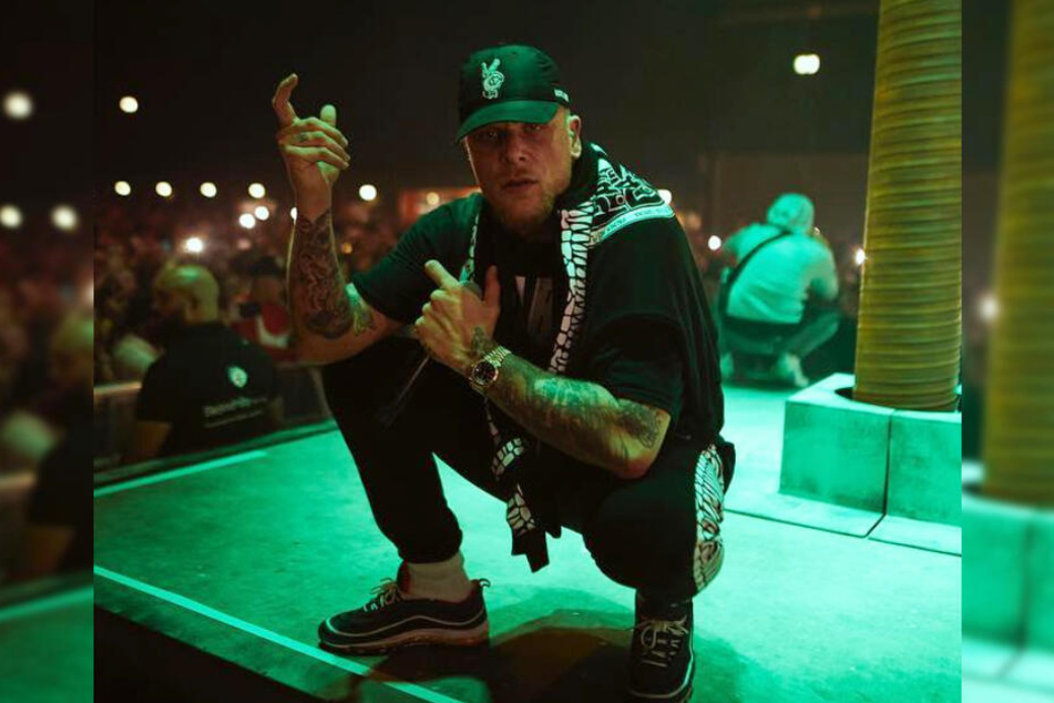 Rapper Bonez MC zeigt sich auf der Bühne mit einer Waffen-Bewegung.