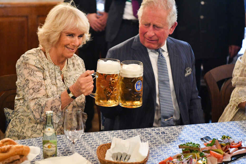 Der britische Thronfolger Prinz Charles und seine Ehefrau Camilla stoßen mit Maßkrügen an im Hofbräuhaus.