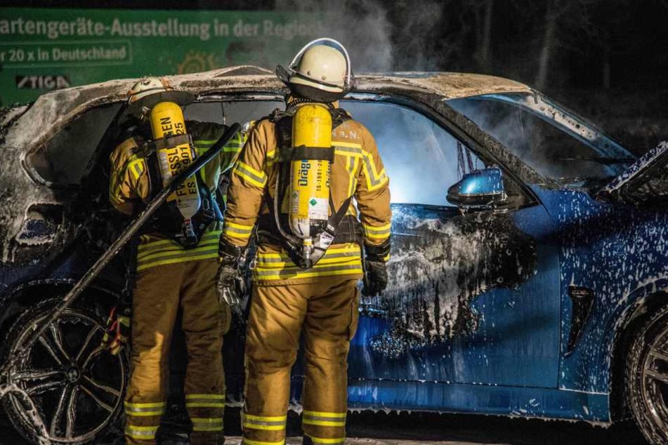 Mittels Schaum schafft es die Feuerwehr, das Feuer im SUV zu löschen.