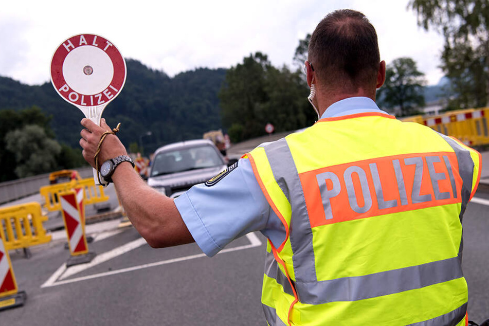Ein Grenzpolizist stoppt ein herannahendes Auto zur Kontrolle.
