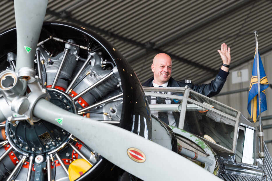 Uwe Wendt, Chefpilot der Ju 52 winkt in Hamburg im Hangar auf der Lufthansa Basis Hamburg aus dem Cockpit des Flugzeugs.