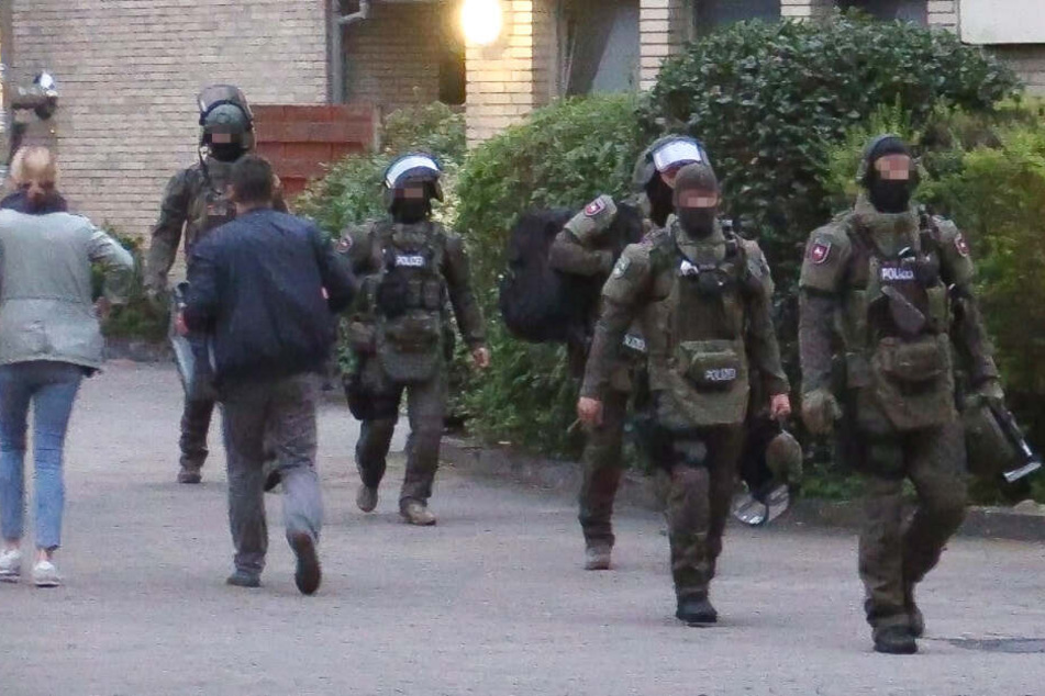 Mitglieder des SEK kommen aus der gestürmten Wohnung zurück.