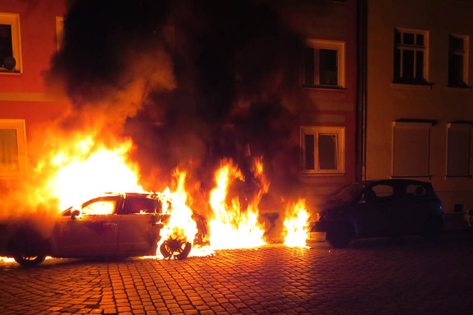 Das Feuer des angezündeten PKW griff auf benachbarte Fahrzeuge sowie die Hausfassade über.