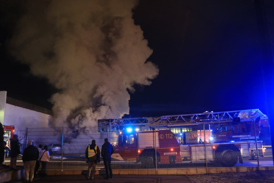 Ein Feuerwehrauto steht am Donnerstagabend vor einem Gebäude einer Druckerei, aus dem Rauch aufsteigt, in Heidenheim. (Archivbild)
