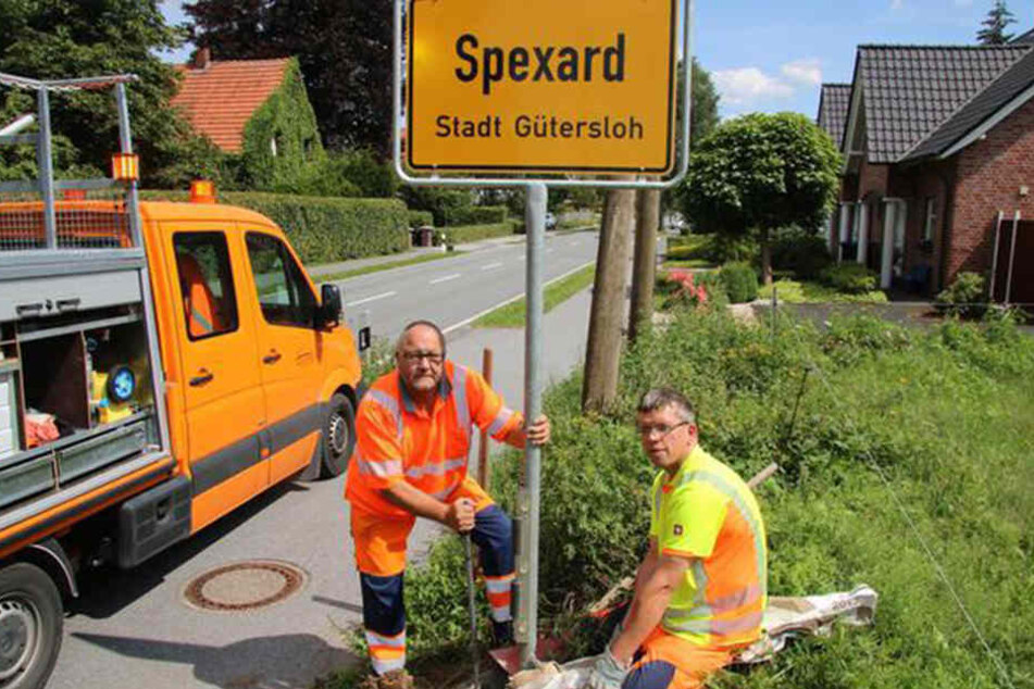 Meinolf Huster (l.) und Martin Hano vom Kreisbauhof sorgen dafür, dass das Schild wieder fest an seinem Platz steht.