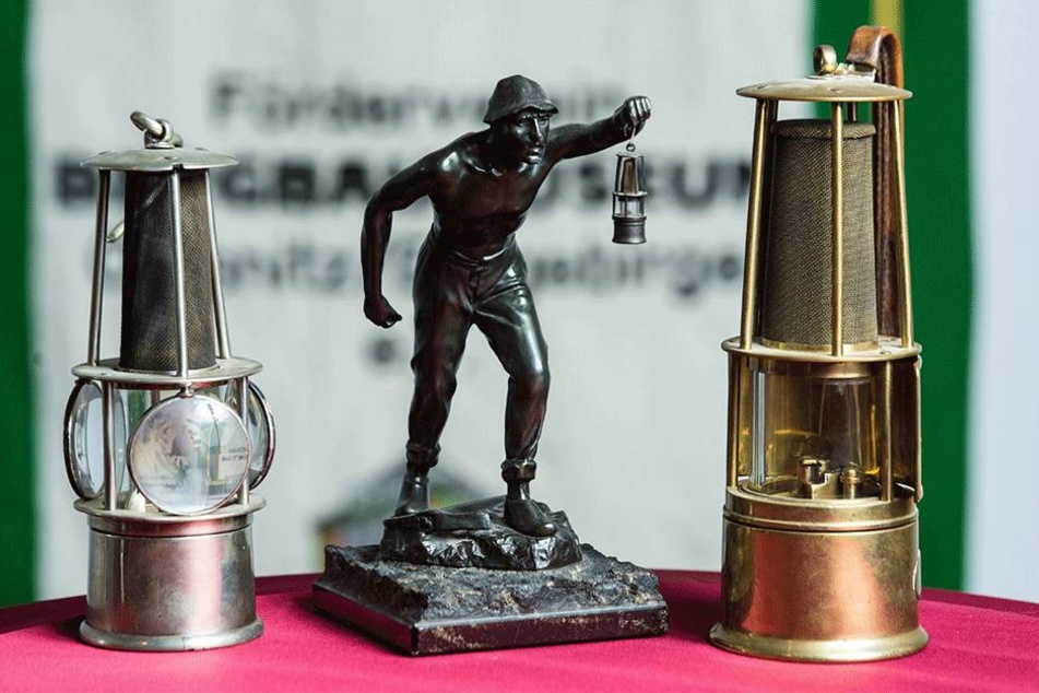 Zwei Grubenlampen und eine Bergarbeiterstatue.